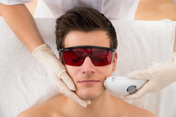 Мужчина в защитных очках на процедуре лазерной эпиляции лица