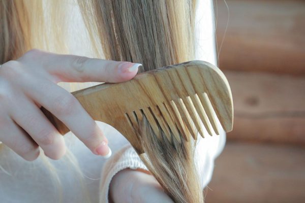 Девушка расчёсывает волос деревянным гребнем