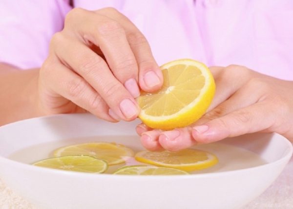 Руки девушки и ванночка для ногтей с лимоном