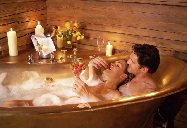 Женщина и мужчина в ванне с клубникой