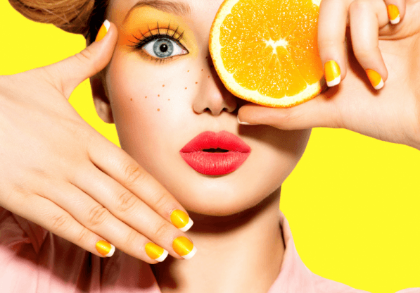 Девушка с веснушками и апельсином у лица