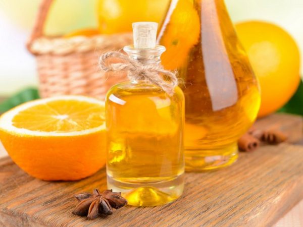 Эфирное масло апельсина в прозрачном флаконе и плоды