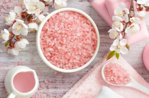 Розовая морская соль в белой ёмкости и цветы