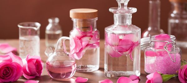 Розовая вода в прозрачных флаконах и лепестки роз