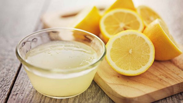 Лимонный сок в прозрачной пиале и лимоны