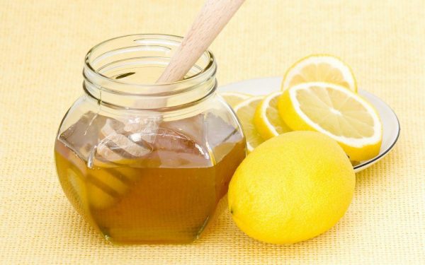 Мёд в прозрачной банке, порезанный лимон на тарелке