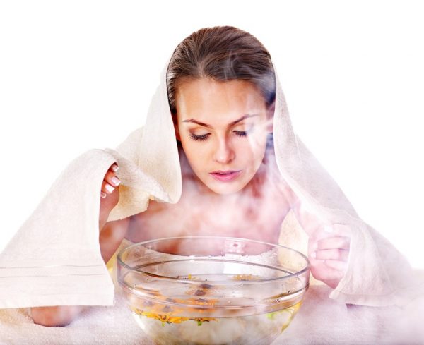 Женщина, укрытая полотенцем, смотрит на прозрачную ёмкость с кипятком