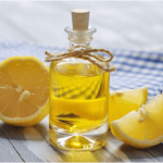 Эфирное масло лимона в прозрачном флаконе и плоды в разрезе