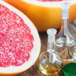 Эфирное масло грейпфрута в прозрачных флаконах и плоды в разрезе
