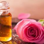 Эфирное масло розы в прозрачном флаконе и цветы