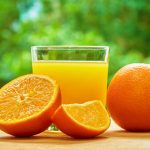 Сок апельсина в прозрачном стакане и фрукты